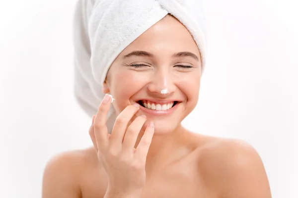 Cheerful attractive young woman with face cream on her nose — Stock Photo, Image