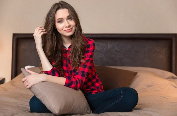 Happy woman sitting on the bed with pillow — Stock Photo, Image