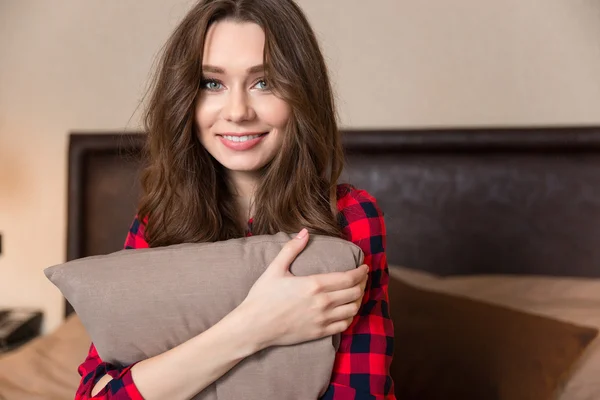 Smiling woman sitting on the bed with pillow — Stock Photo, Image