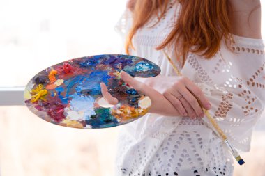 Art palette with oil paints and brush holded by woman 