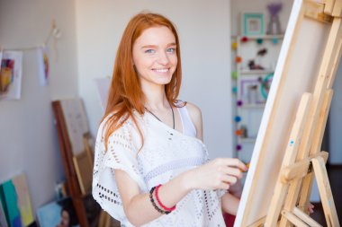 Lovely cute joyful woman artist enjoying drawing in art workshop clipart