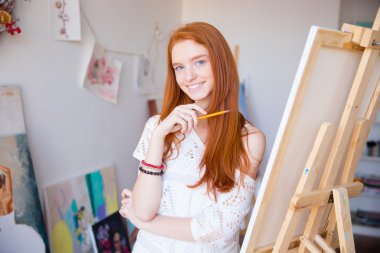 Cheerful attractive young woman artist painter sketches by pencil 