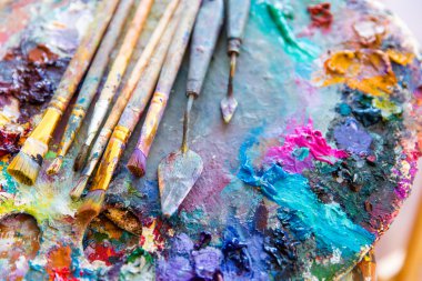 Bright mixed color paints on art palette with paintbrushes 