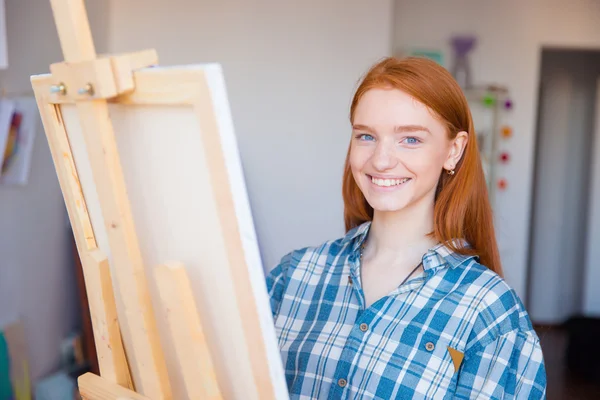 Pretty cheerful young woman painter painting in art studio — Stock Photo, Image