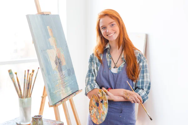 Happy satisfied woman painter finished painting picture in art studio — 스톡 사진