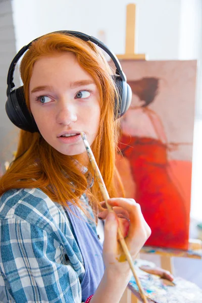 Pintora joven atractiva y pensativa que escucha música y pintura — Foto de Stock