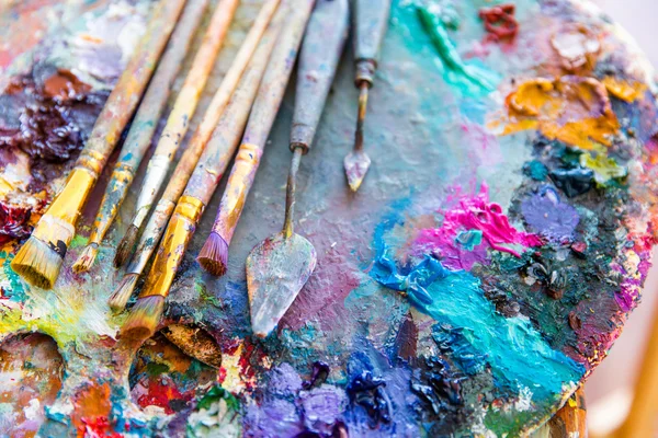 Яркие разноцветные краски на художественной палитре кисточками — стоковое фото