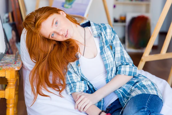 Entspannte nachdenkliche Frau liegt auf weißem Sitzsack im Kunstatelier — Stockfoto