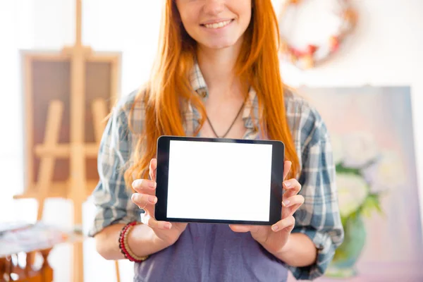 Cheerful beautiful young woman standing and holding blank screen tablet — Stock fotografie