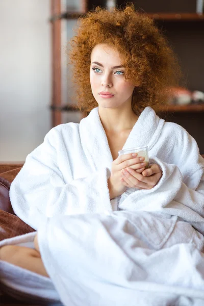 Beautiful pensive woman in white bathrobe sitting and relaxing — Stock Photo, Image
