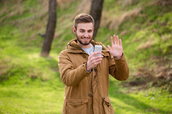Мужчина делает видеозвонок на улице на смартфоне
 