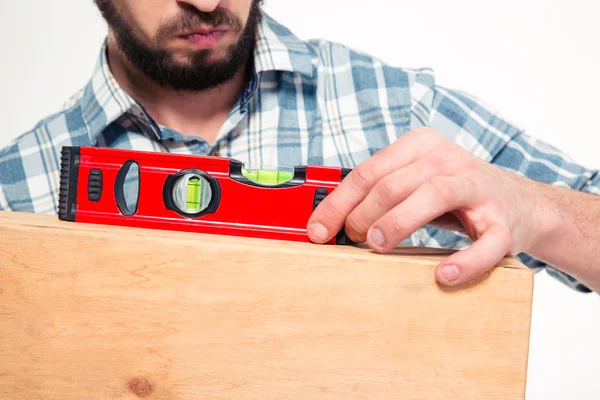 Close up of concenrated bearded young man using spirit level — Stock Photo, Image