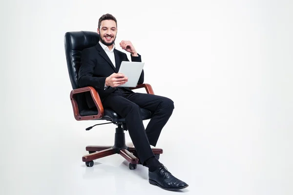 Cheerful  businessman sitting in office chair and using tablet — Stock Photo, Image