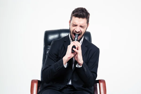 Desperate businessman sitting in office chair with gun into mouth — Stockfoto