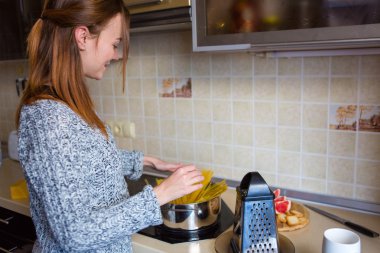 Sevimli gülümseyen genç kadın mutfakta makarna yapma