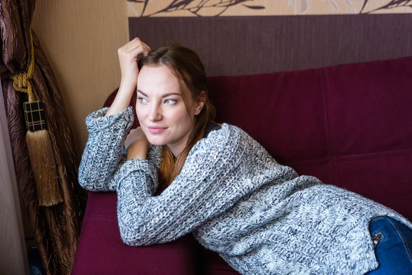 Thoughtful lovely young female lying on couch at home — Stock Photo, Image