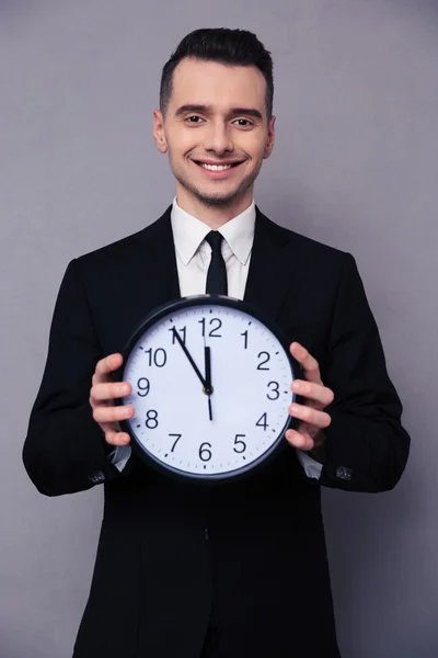 Homme d'affaires souriant tenant horloge murale — Photo