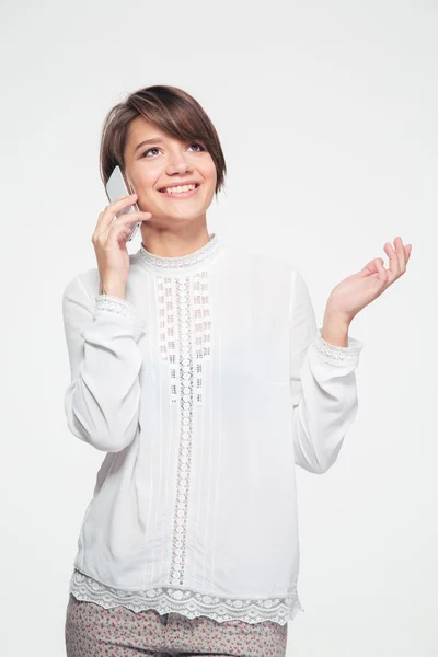 Jovem mulher bonita alegre de pé e falando no telefone celular — Fotografia de Stock