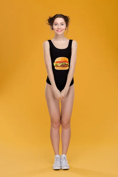 Belle femme souriante en nage avec impression hamburger debout droit — Photo