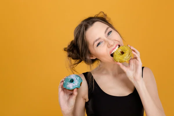 Pretty positive young woman eating colorful donuts — Stock Photo, Image