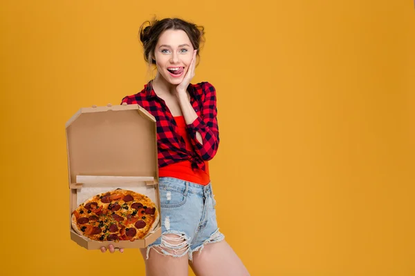 Διασκεδαστικό ελκυστική νεαρή γυναίκα δείχνει γλώσσα και κρατώντας πίτσα — Φωτογραφία Αρχείου