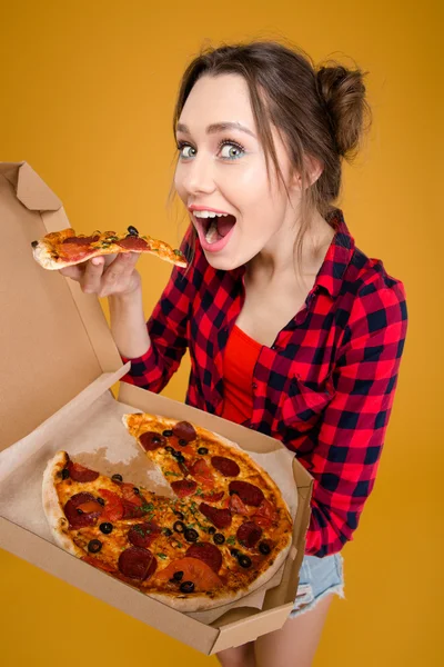 Wanita muda yang gembira berdiri dan mencicipi pizza — Stok Foto