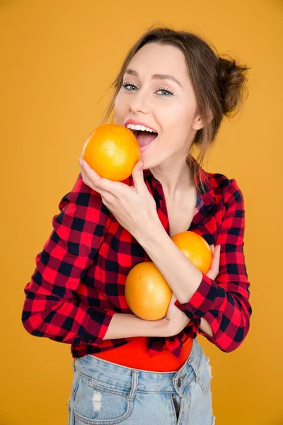 Beautiful smiling young woman in plaid shirt holding grapefruits — Stock Photo, Image
