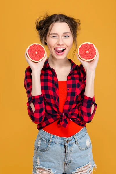 Flörtig leende kvinna blinka och poserar med halvorna av grapefrukt — Stockfoto