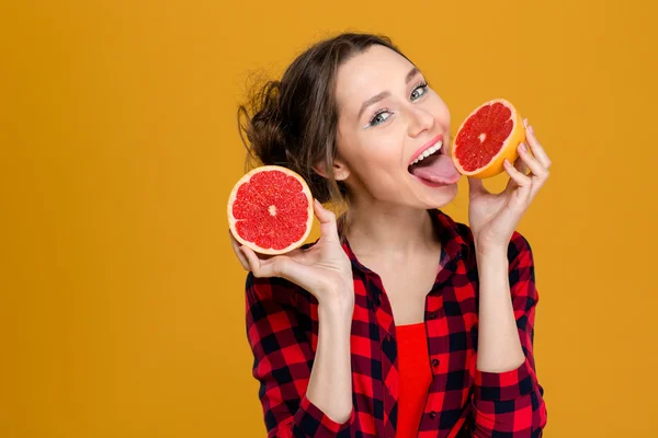 Happy attractive young woman holding and licking half of grapefruit — Stock Photo, Image