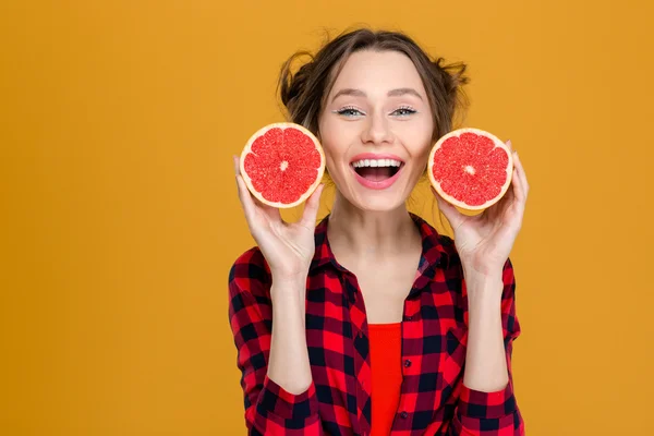 Mujer hermosa sonriente sosteniendo dos mitades de pomelo —  Fotos de Stock