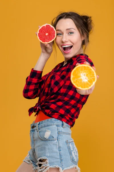 Glada attraktiv kvinna poserar med halvorna av apelsin och grapefrukt — Stockfoto