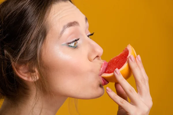 Profil der hübschen jungen Frau, die frische Grapefruit isst — Stockfoto