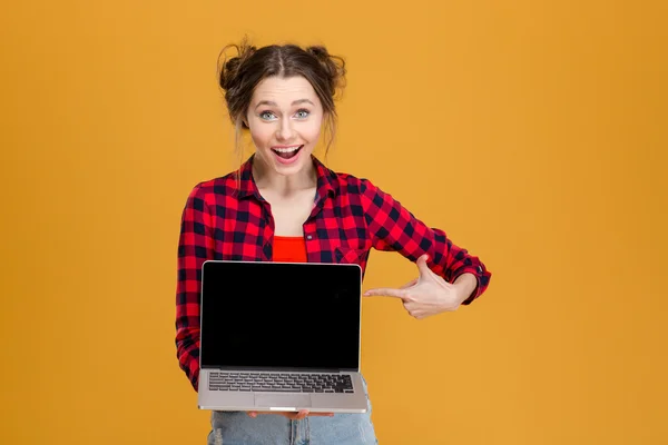 Mujer hermosa alegre sosteniendo y señalando en la computadora portátil de pantalla en blanco —  Fotos de Stock