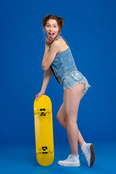 Retrato de comprimento total de uma mulher alegre com skate — Fotografia de Stock