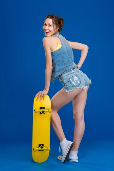 Glad ung kvinna poserar med skateboard — Stockfoto