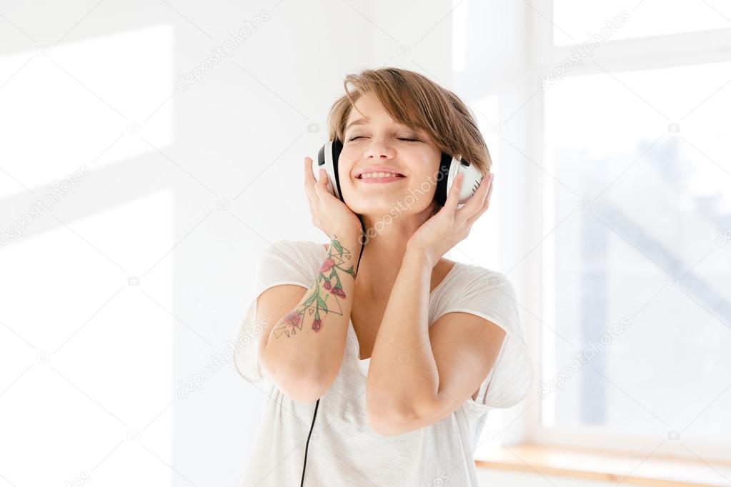 Relaxed happy young woman listening to music using earphones