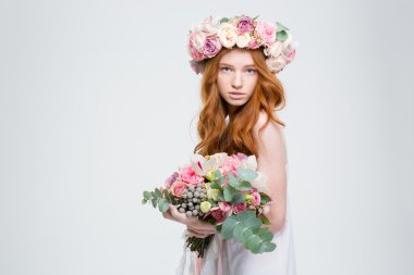 Beautiful female in wreath of roses posing with flower bouquet
