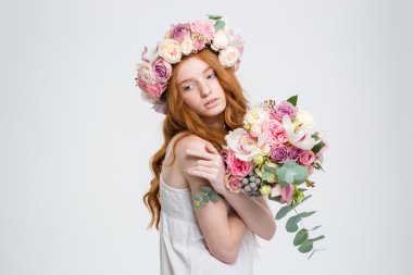 Tender charming woman in wreath posing with bouquet of flowers
