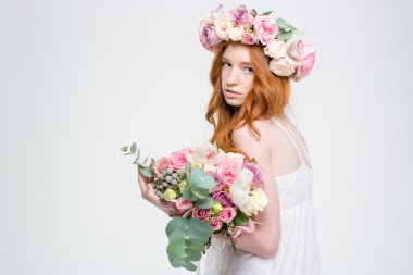 Fashion portrait of beautiful woman in wreath holding flowers bouquet