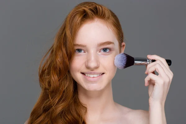Cheerful woman with red hair doing make up on cheeks — Stok fotoğraf