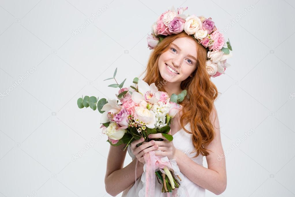 Smiling attractive young woman in wreath holding bouquet of flowers