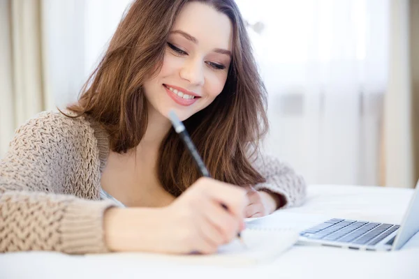 Schön inspirierte lächelnde junge Frau schreibt in Notizblock — Stockfoto