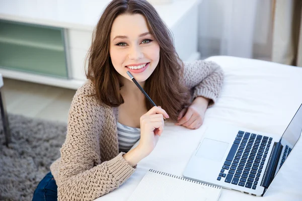 Felice bella giovane donna utilizzando il computer portatile e la scrittura su notebook — Foto Stock