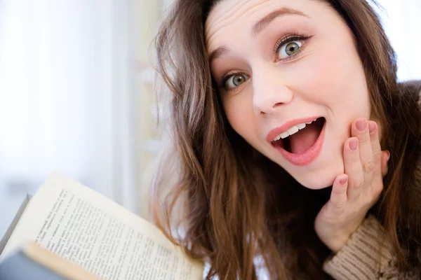Sorpresa bella giovane donna che legge un libro a casa — Foto Stock