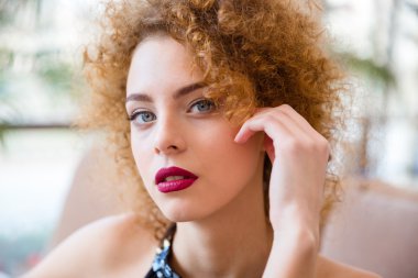 Kameraya bakarak kıvırcık saçlı Kızıl saçlı kadın
