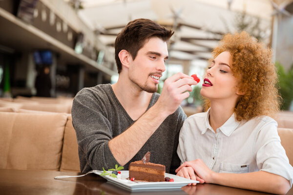 Couple eating cake with strawberry in restaurant