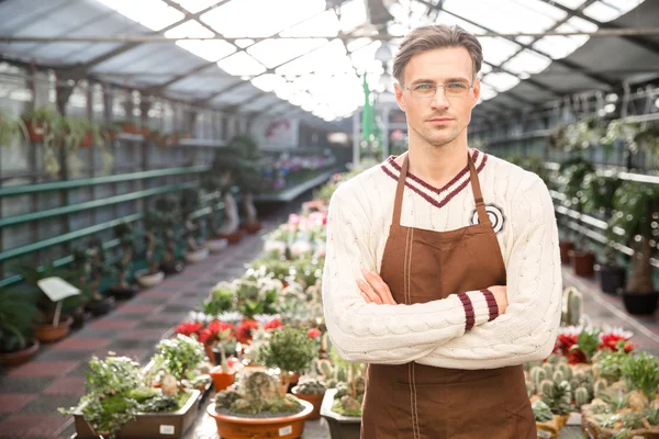 Confident man gardener standing in greenhouse with arms crossed — Stock Photo, Image