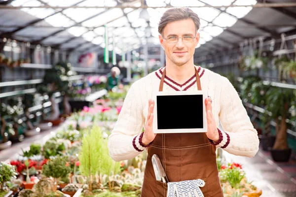 Gärtner zeigt leeres Tablet im Gewächshaus — Stockfoto