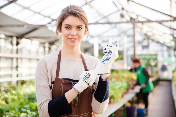 Happy young woman gardener in garden gloves and apron — Zdjęcie stockowe