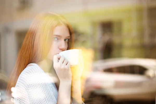 Woman drinking coffee and looking at window — Stockfoto